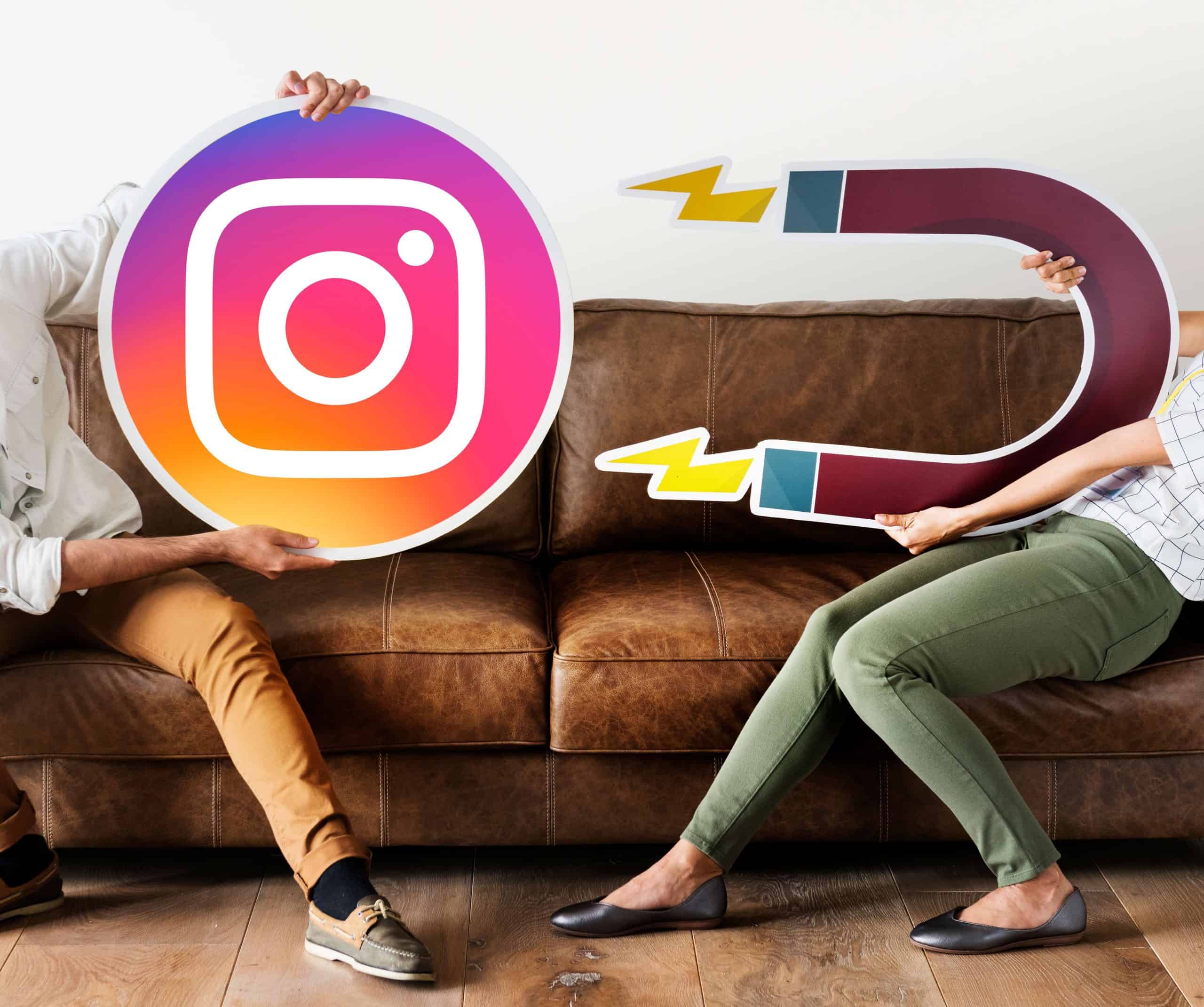 Dos personas sentadas en un sofá sujetando grandes iconos de cartón, uno con el logotipo de Instagram y otro con un imán, simbolizando la atracción de seguidores y el crecimiento orgánico en redes sociales. Representa la idea de cómo aumentar visibilidad, alcance y engagement en Instagram mediante estrategias de contenido efectivas y coherentes. Imagen conceptual sobre marketing digital, redes sociales y atracción de audiencia, perfecta para artículos de branding, social media y crecimiento orgánico. Palabras clave: crecer en Instagram, atraer seguidores, marketing digital, engagement, estrategia Instagram 2025, Tu Creativa, redes sociales.
